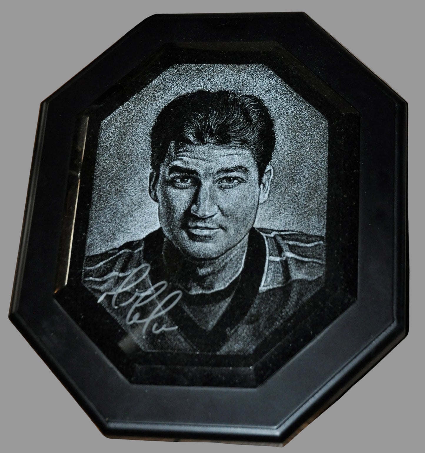 Portrait of a man in a black frame on a wooden surface. Mario Lemieux marble piece.